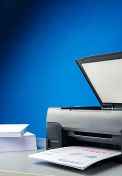Laser printer on desk against blue background close up